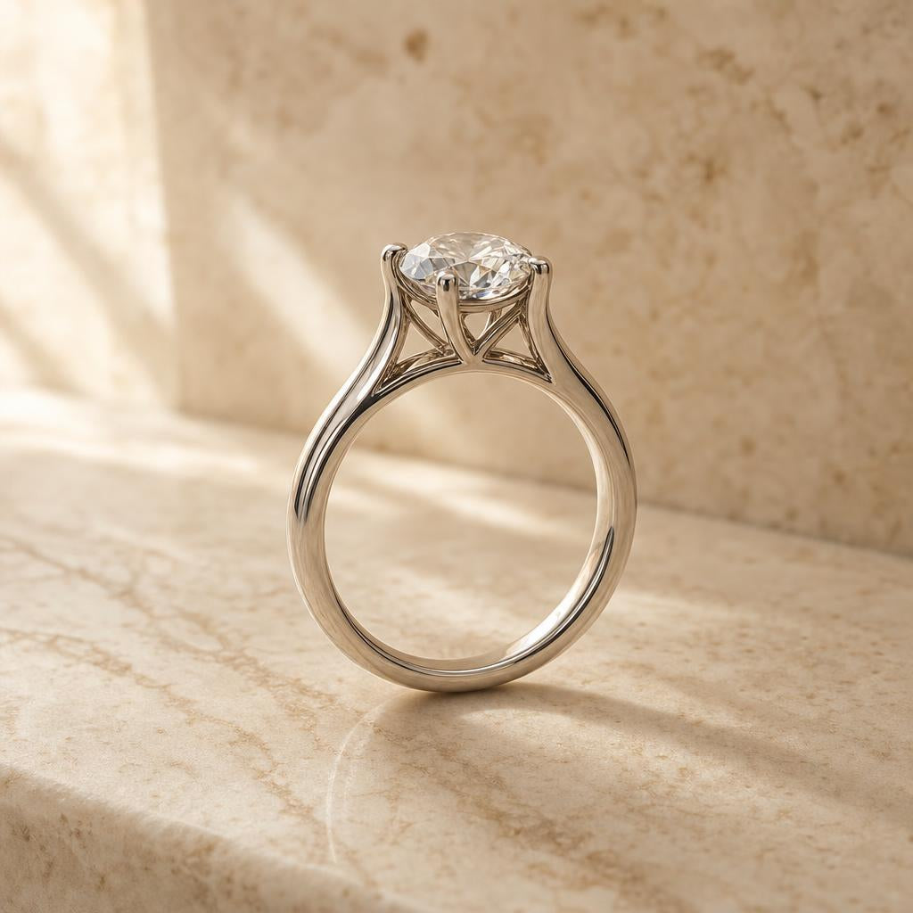 Round brilliant solitaire ring with cathedral setting arches on warm stone surface