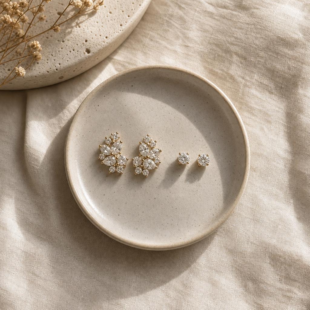 Two contrasting pairs of earrings, bold and minimalist, on linen