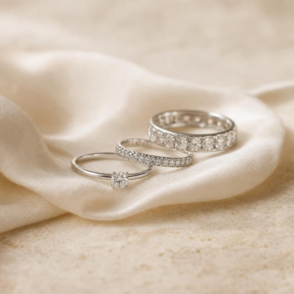 Three rings of different band widths arranged on warm ivory silk fabric
