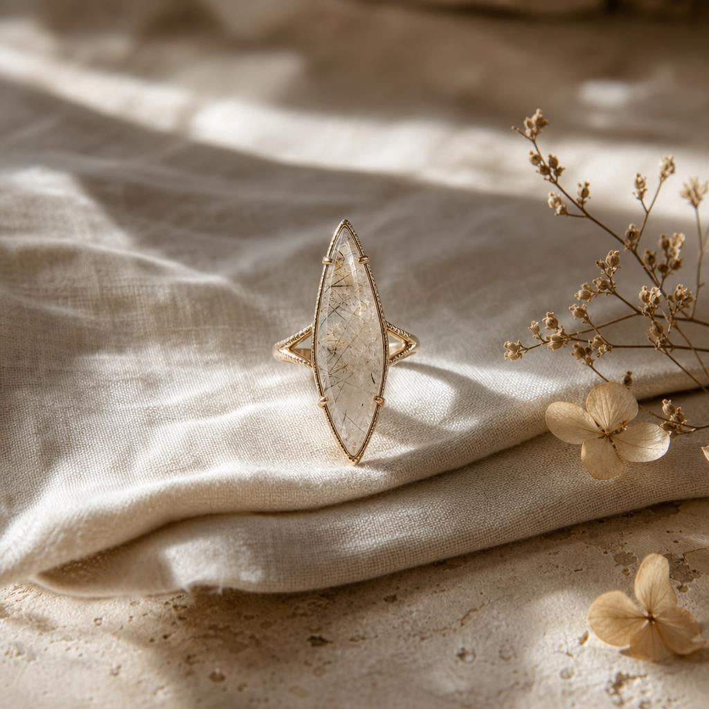 Elongated marquise-cut ring resting on ivory linen with soft warm light