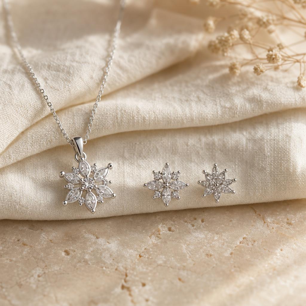 Silver pendant necklace and stud earrings on cream linen in soft light