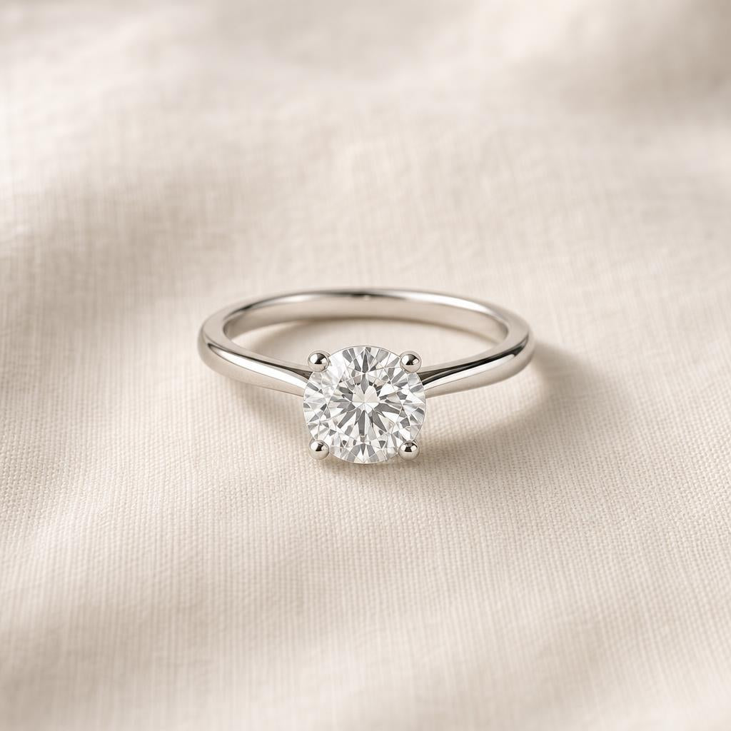 Minimalist round solitaire diamond ring resting on warm cream linen