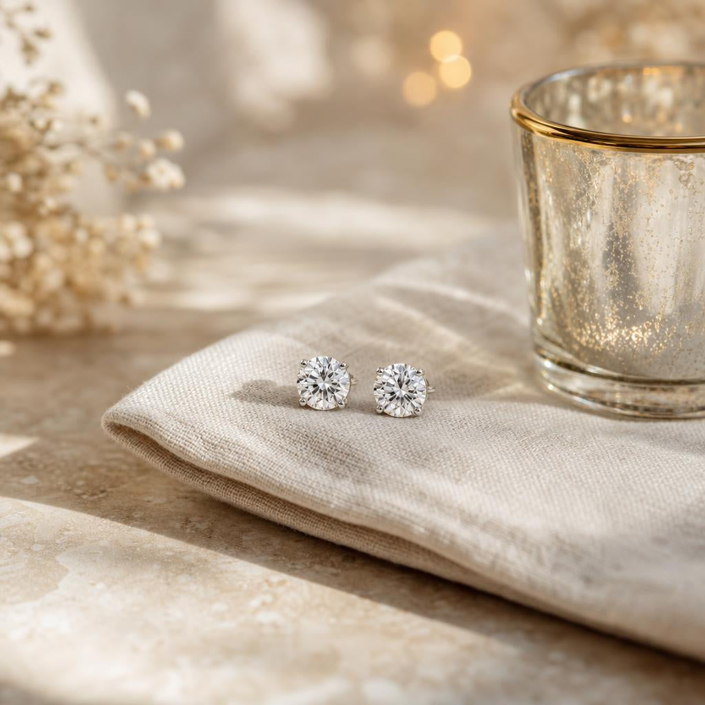 Pair of sparkling round stud earrings on cream linen with soft festive lights