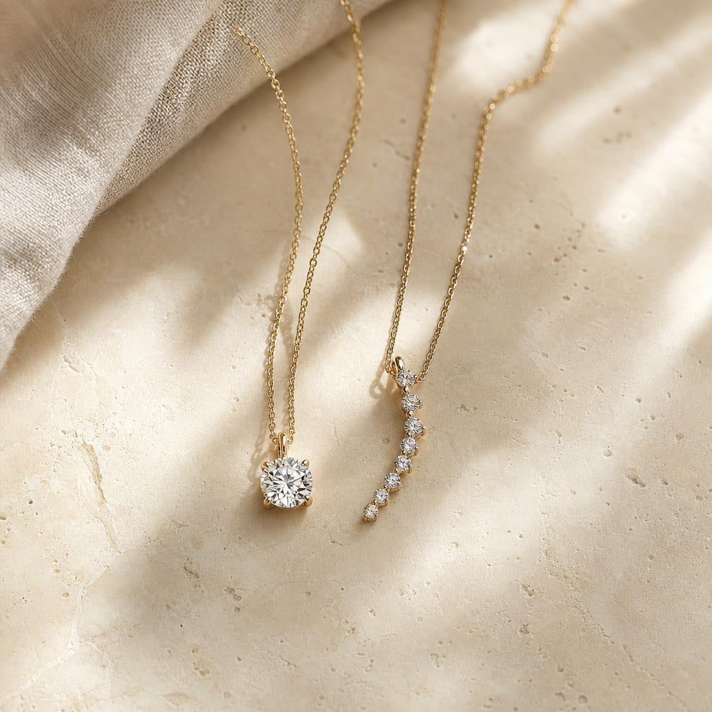 Single stone pendant necklace beside a multi-stone cluster pendant on cream stone