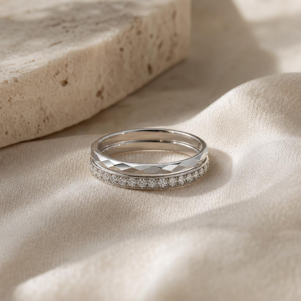 Two slender silver rings stacked together on a soft cream surface