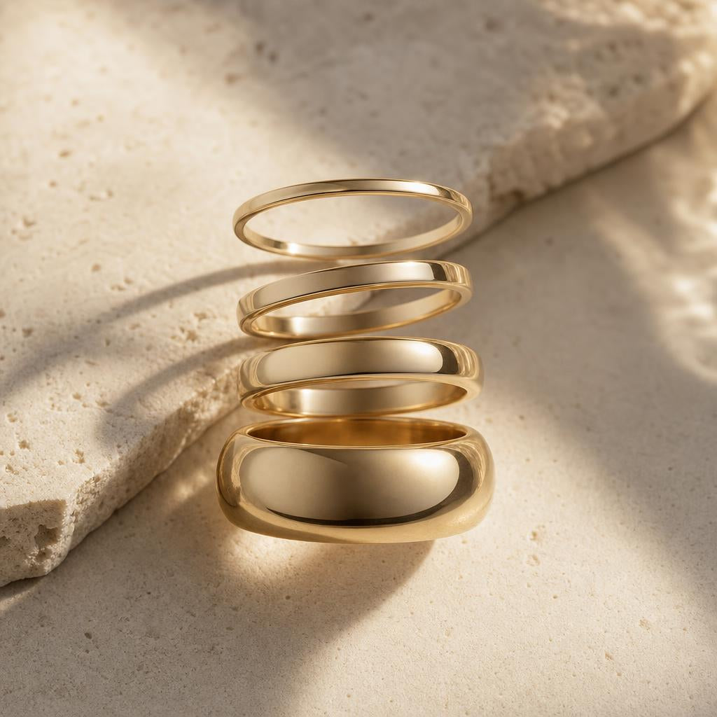 Wedding bands of varying widths arranged in a cascading stack on stone