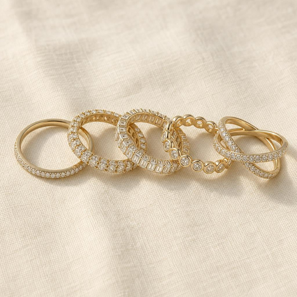 Five delicate stacking rings arranged on cream linen in an editorial flat-lay