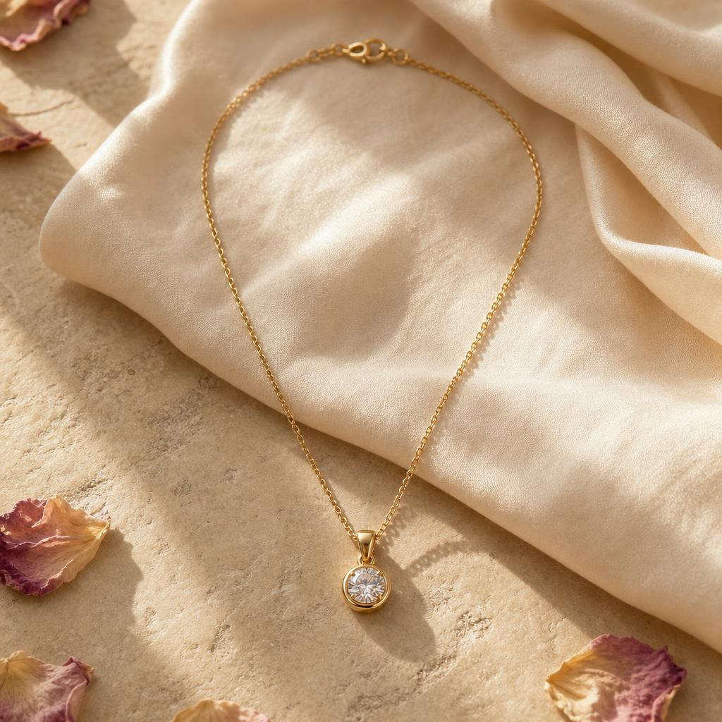 Delicate gold pendant necklace resting on warm cream fabric