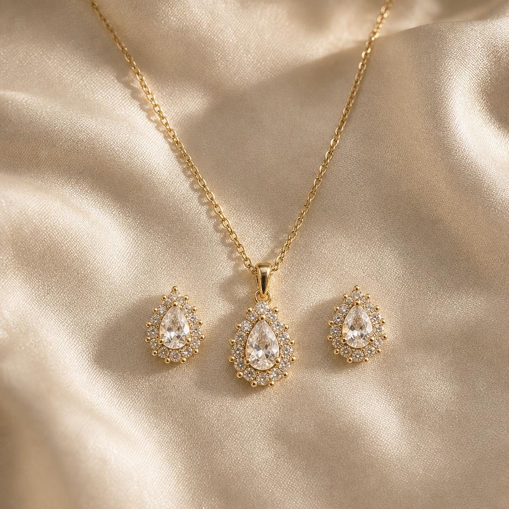 Matching pendant necklace and stud earrings arranged together on cream silk