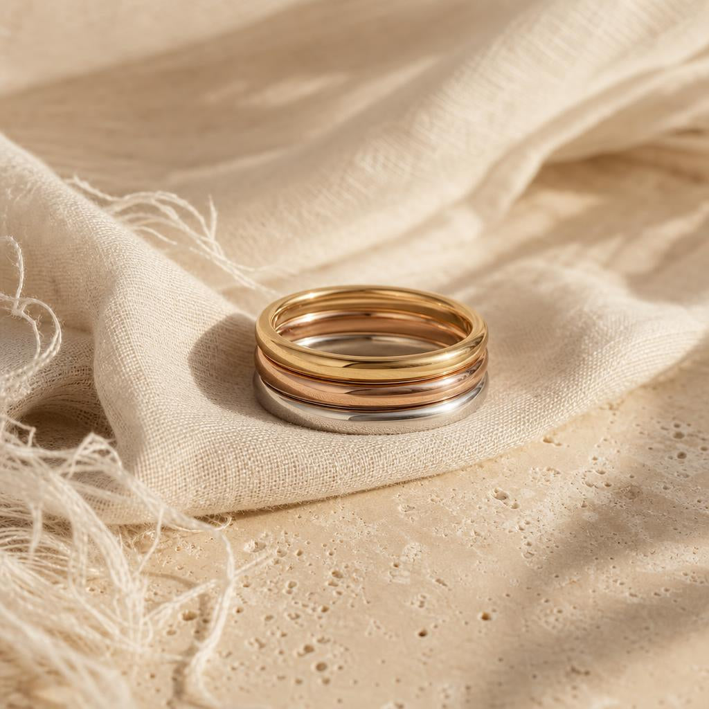 Three stacked rings in mixed gold tones on ivory linen
