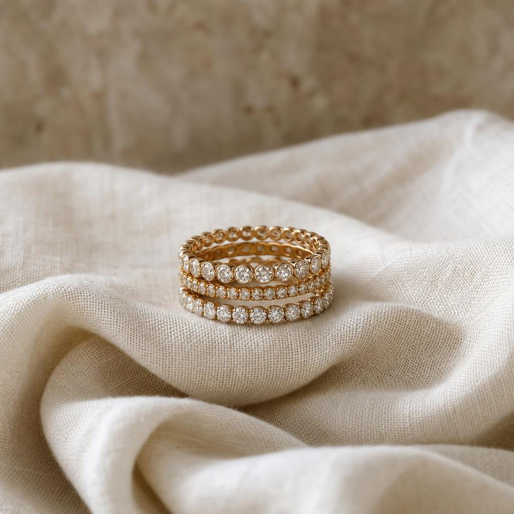 Three delicate diamond eternity rings stacked on soft ivory linen fabric