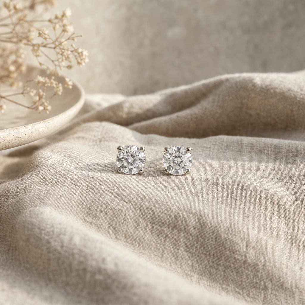 Pair of clear round stud earrings on oatmeal linen in soft light
