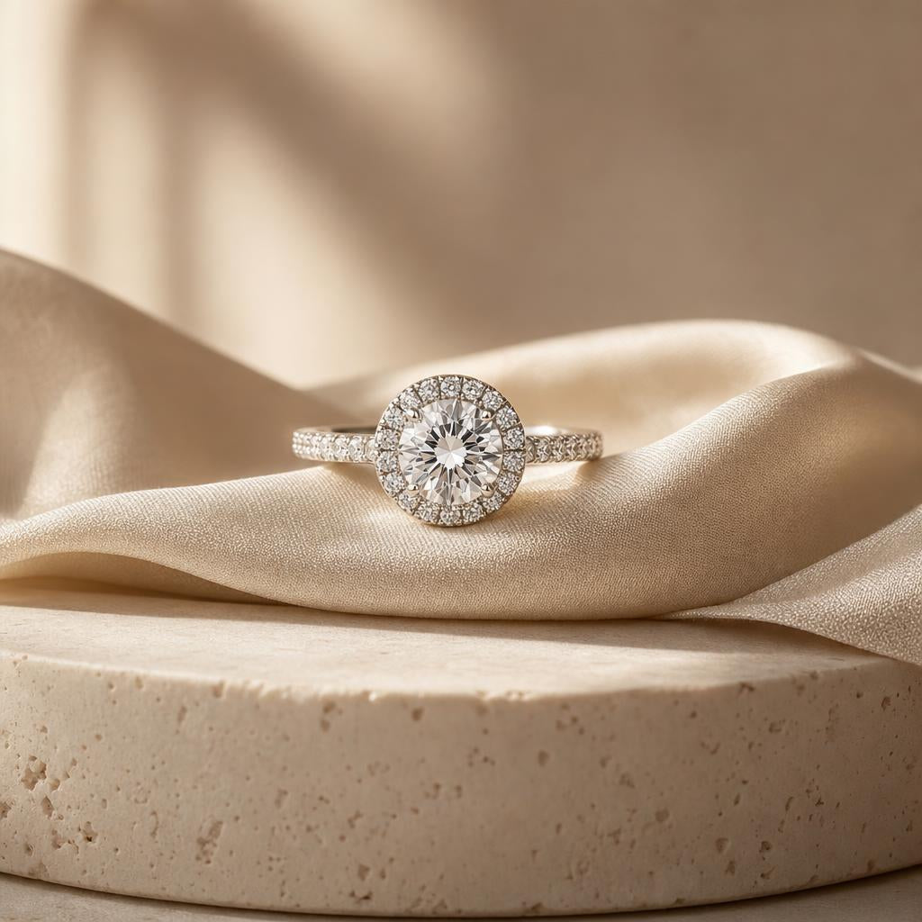 Sparkling halo engagement ring on warm cream fabric with soft light
