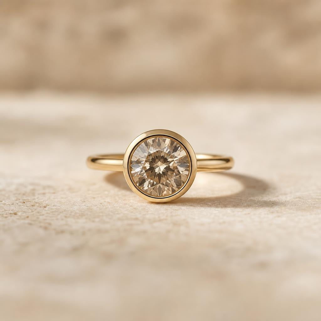A single ring with a round gemstone in a smooth bezel setting on a cream background