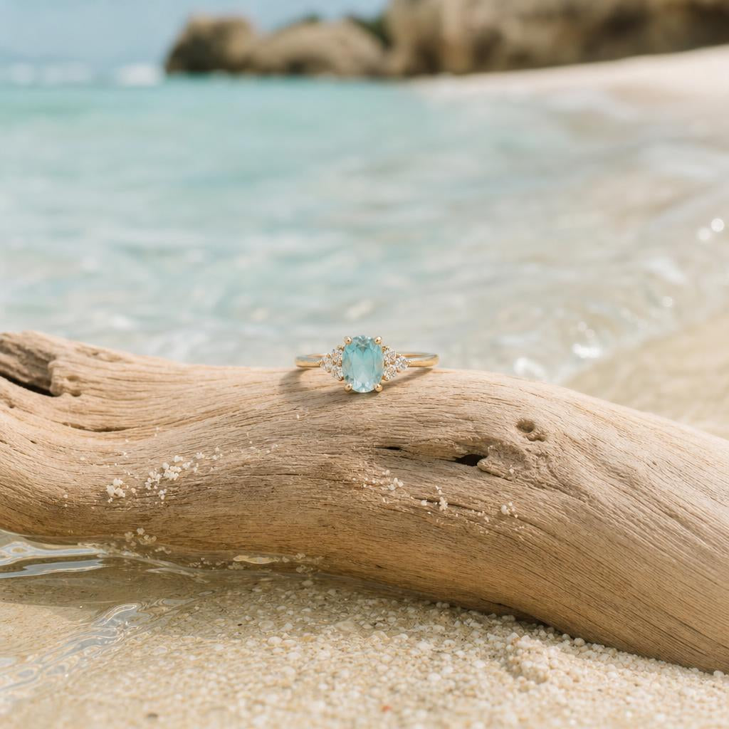 A ring resting on driftwood at the edge of turquoise ocean water
