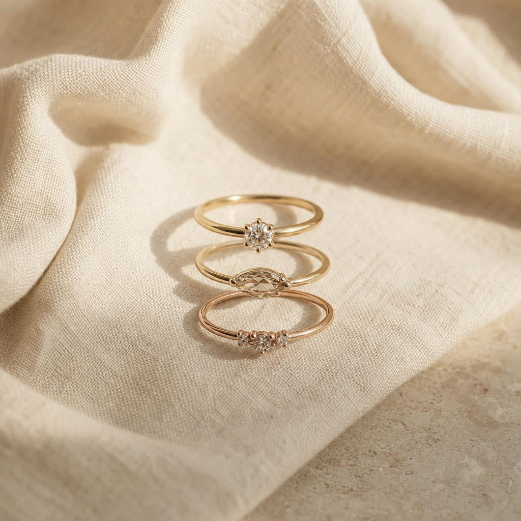 Three minimalist rings arranged in a row on warm cream linen fabric