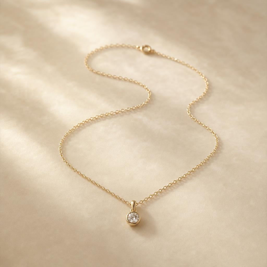 Delicate gold pendant necklace coiled on cream silk background
