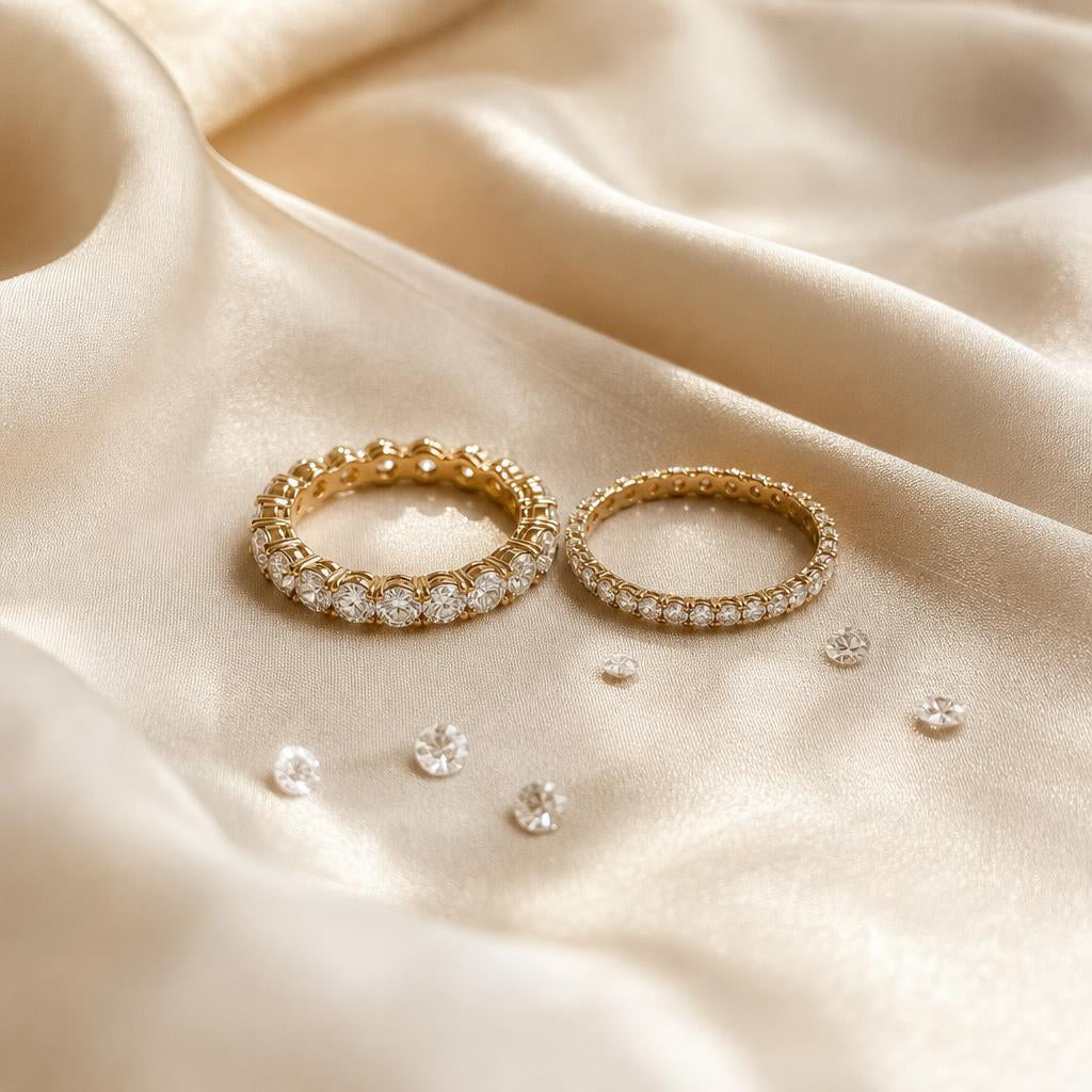Two eternity-style rings resting together on soft cream silk fabric