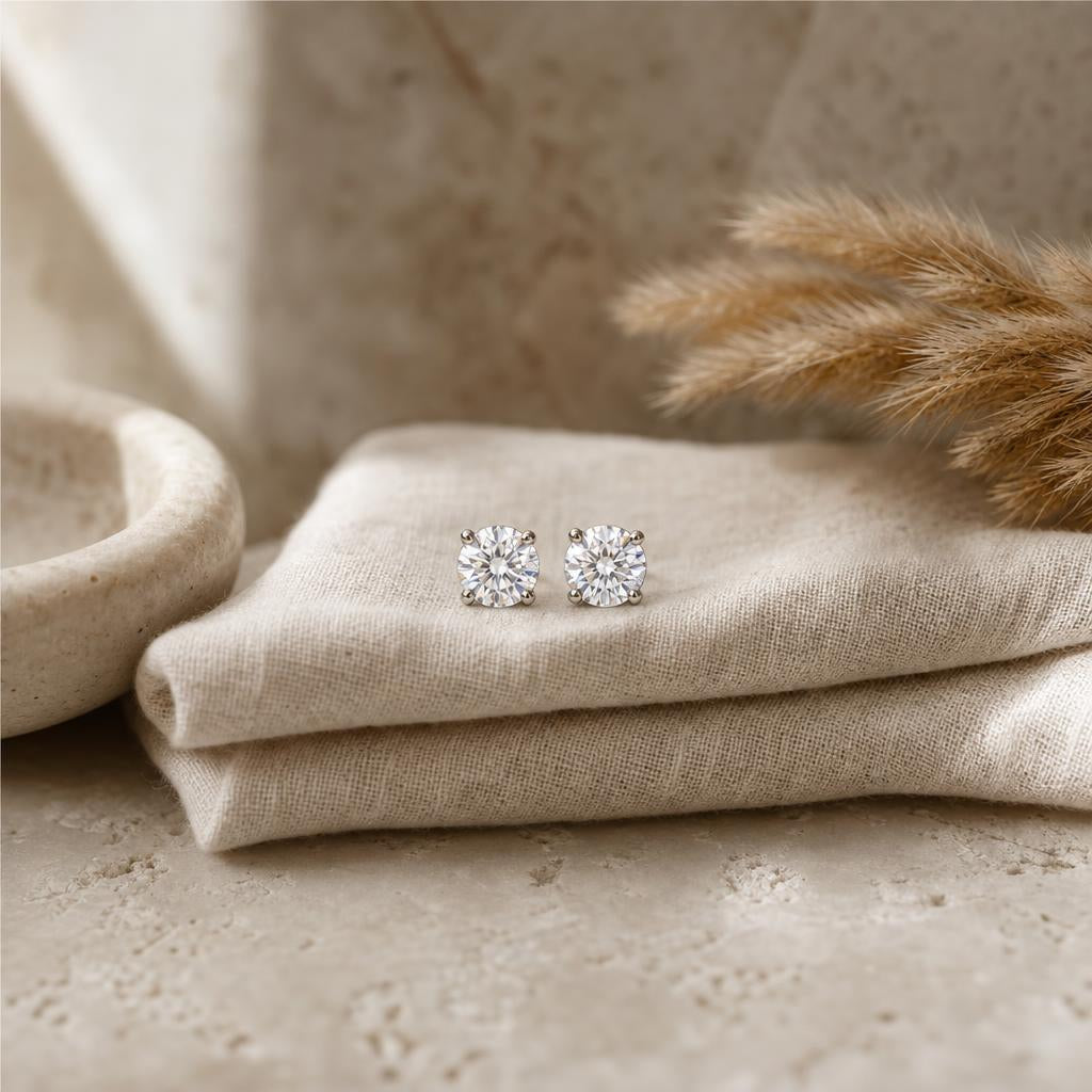 Pair of sparkling stud earrings on cream linen in soft natural light
