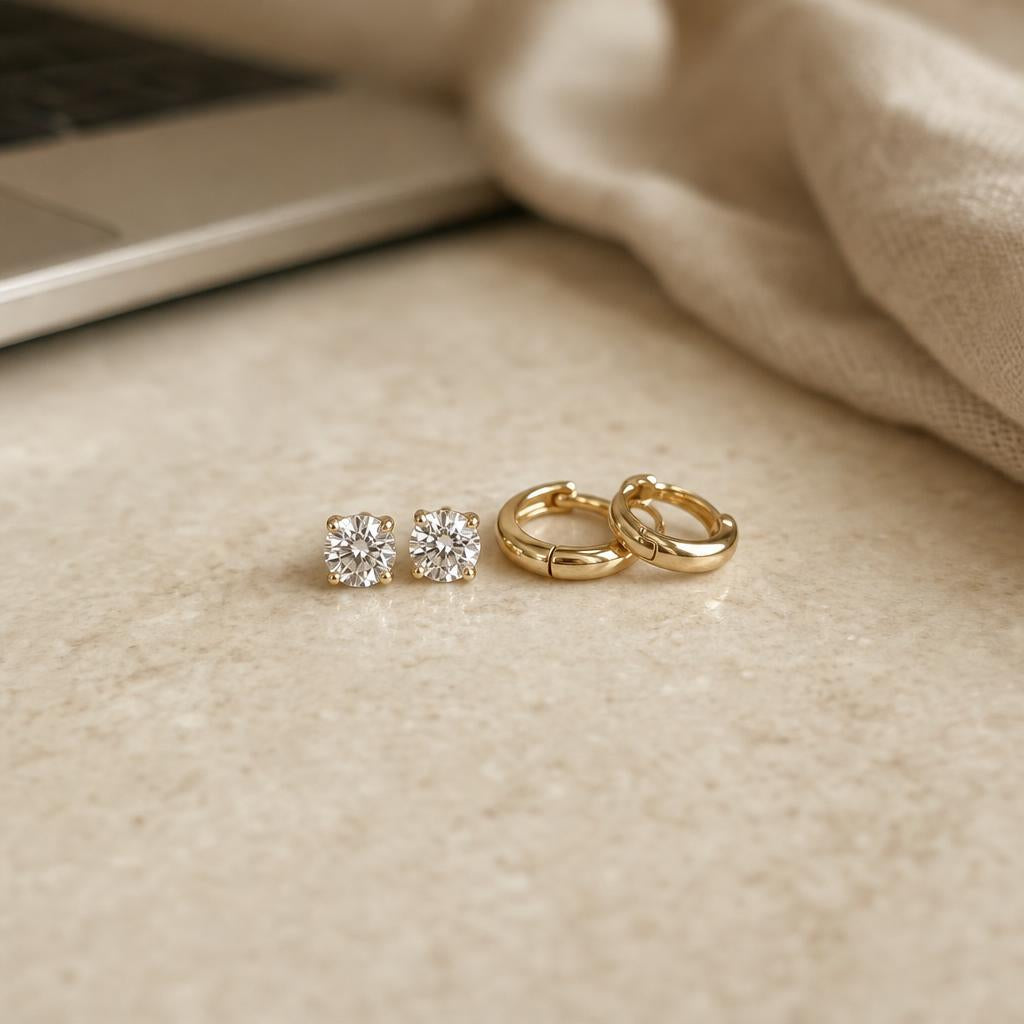 Round stud earrings and small huggie hoops on cream stone with soft window light