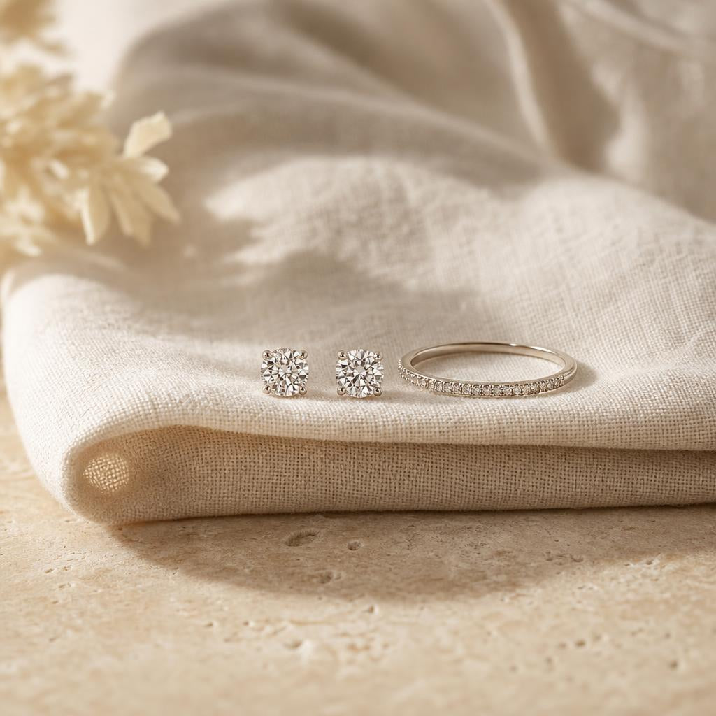 Pair of round stud earrings and slim ring band on cream linen