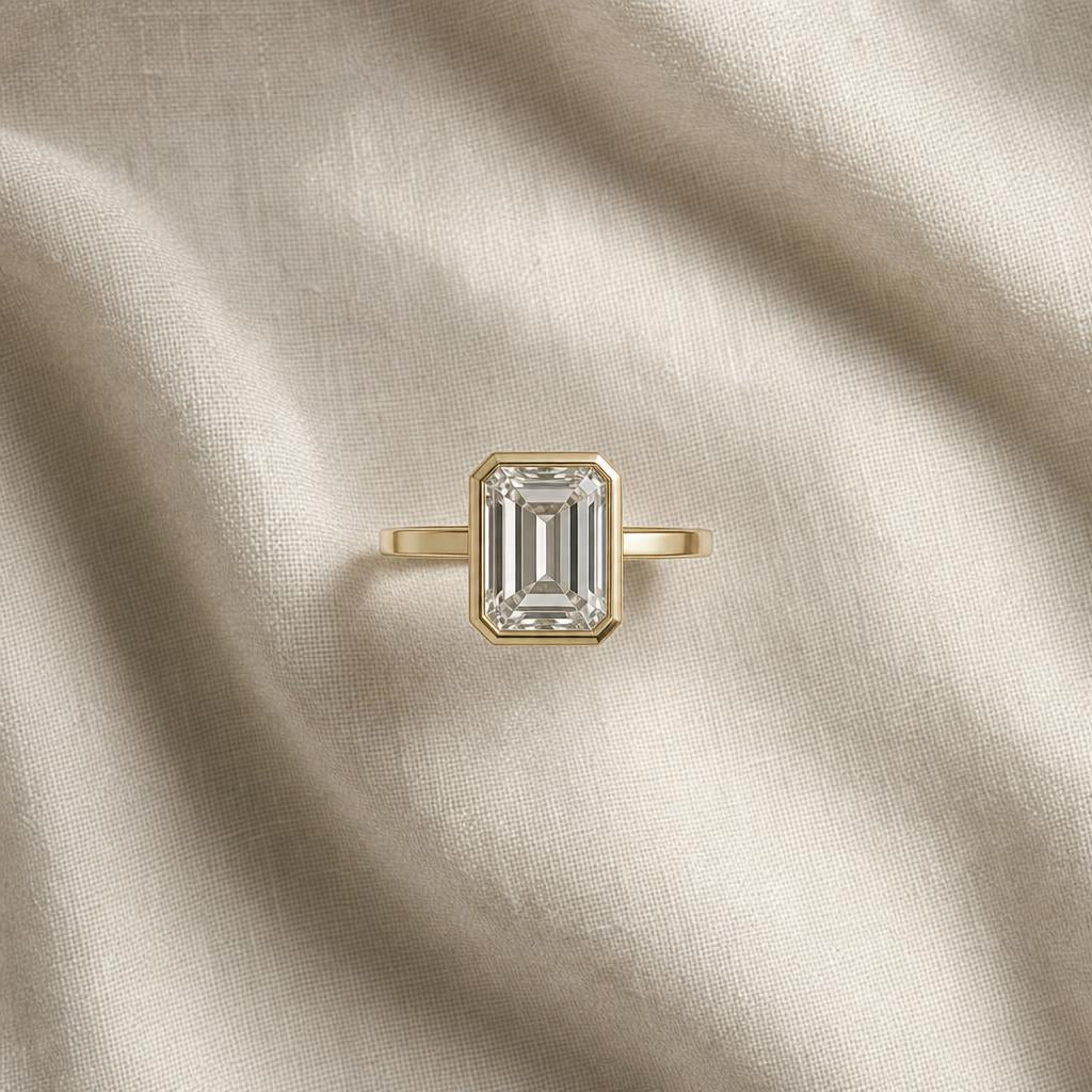 Emerald-cut ring centered on a neutral linen surface in warm light