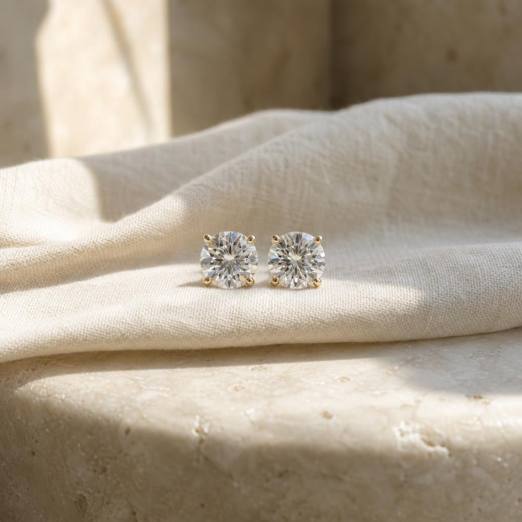 Pair of sparkling round stud earrings on warm cream linen