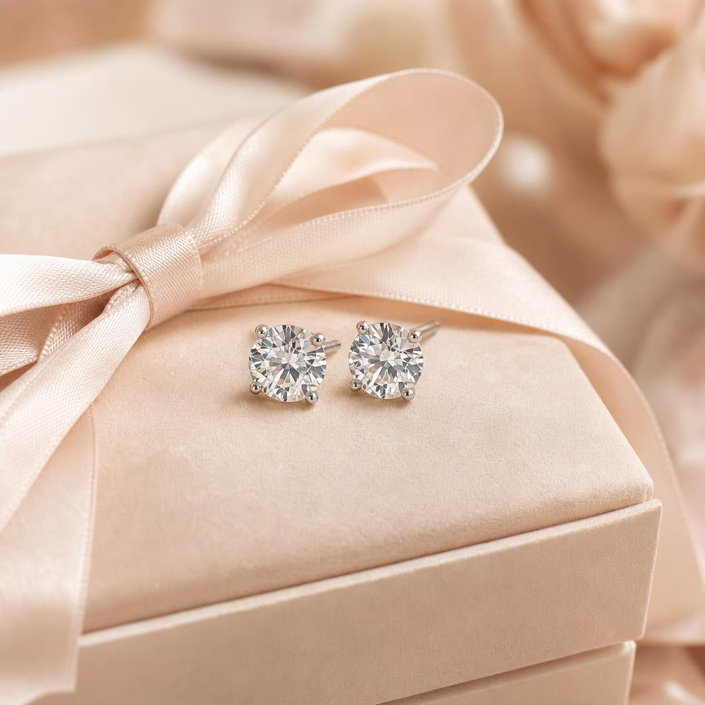 Diamond stud earrings resting on a wrapped gift box, warm cream background