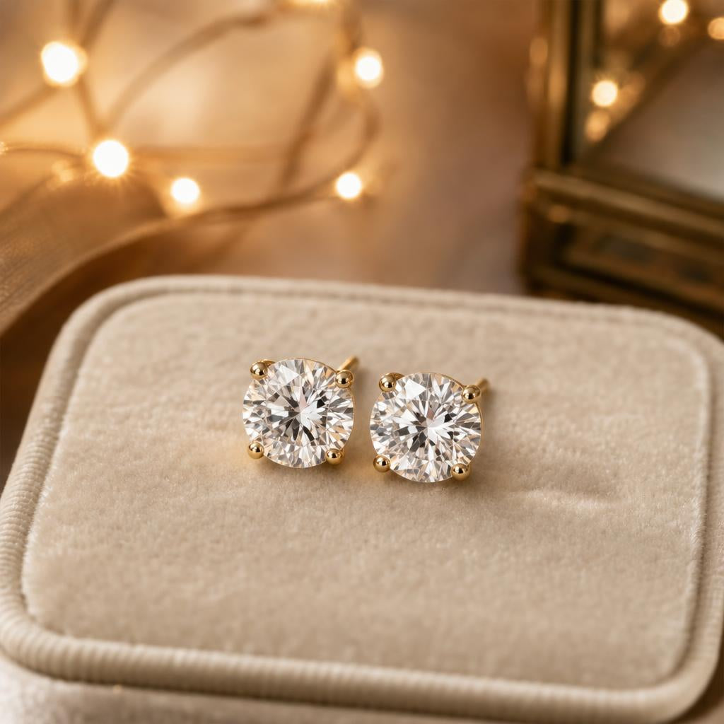 Sparkling diamond stud earrings on cream velvet with soft golden holiday lights