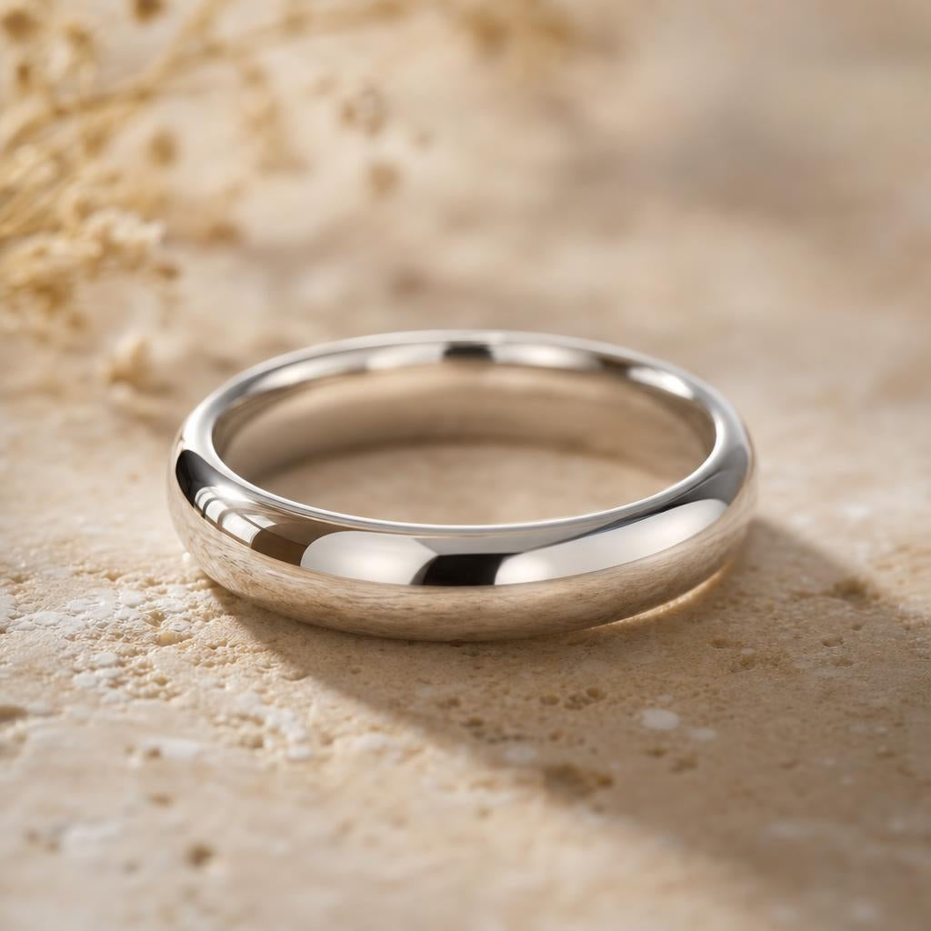 Bright polished silver ring band on a warm cream stone surface