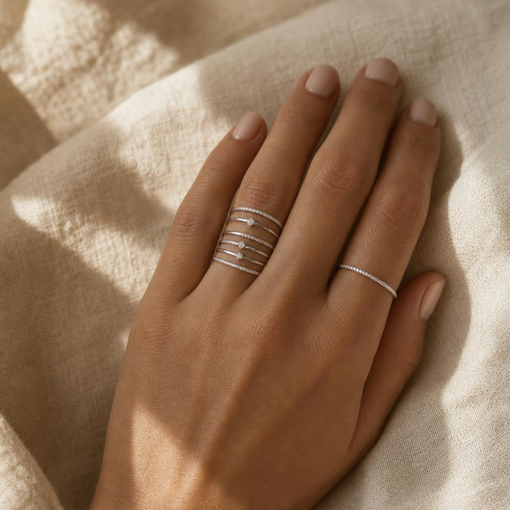 Hand wearing stacked sterling silver rings in a vertical column on one finger