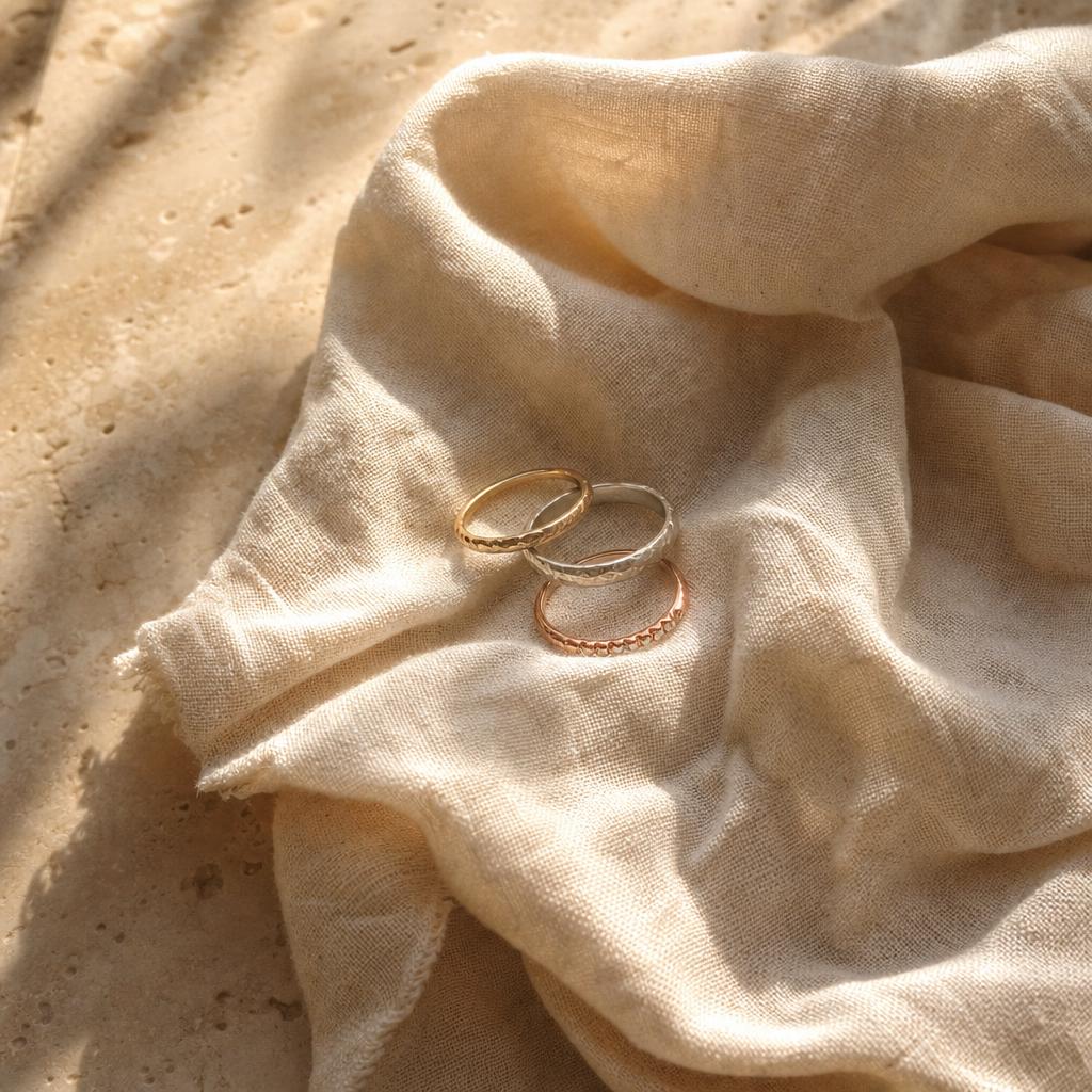 Three delicate mixed-metal rings resting on soft folded linen fabric