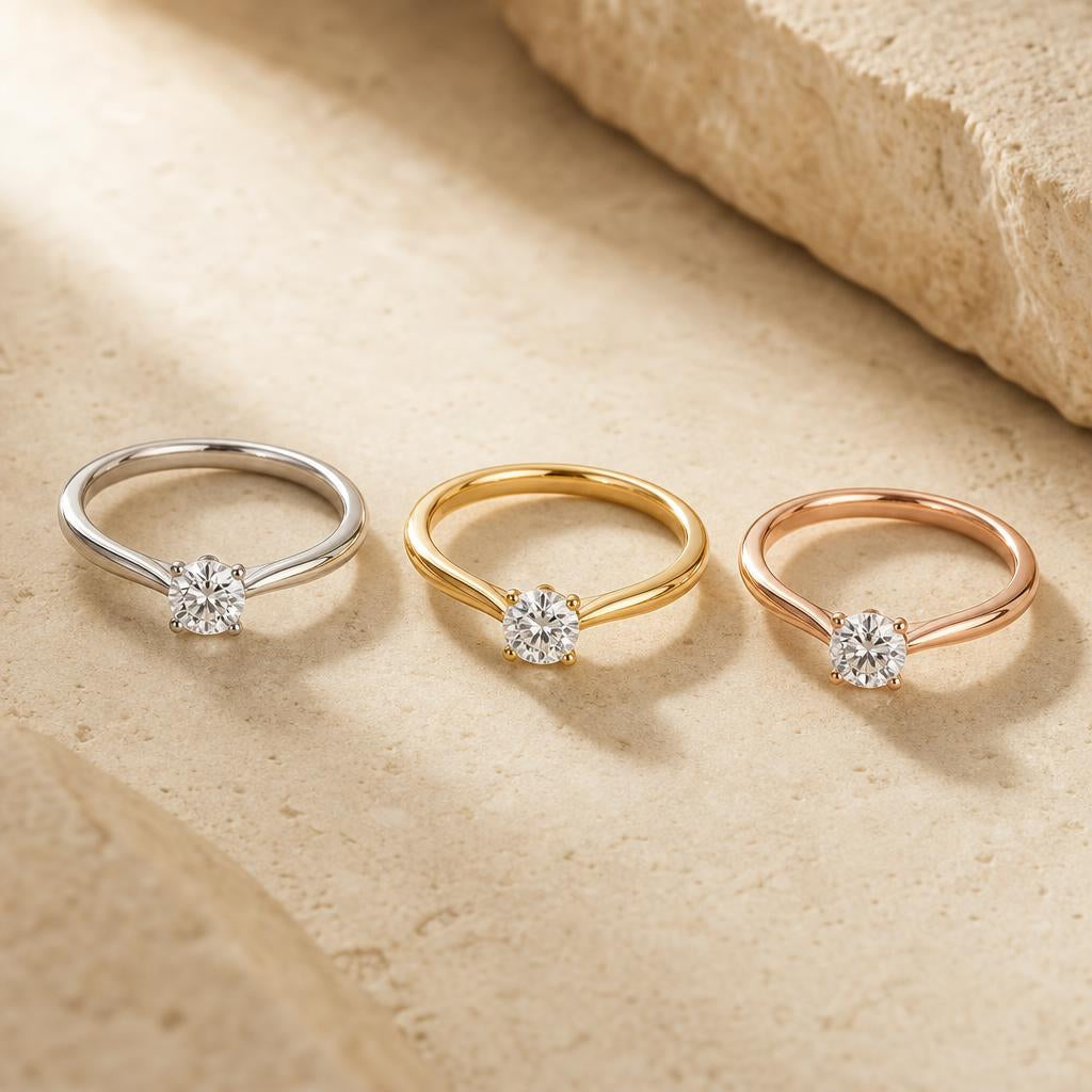 Three rings in silver, yellow gold, and rose gold arranged on warm cream stone