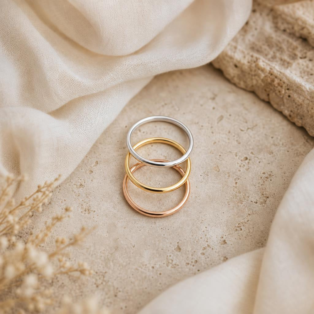 Three stacking rings in platinum, gold, and rose gold on a cream background
