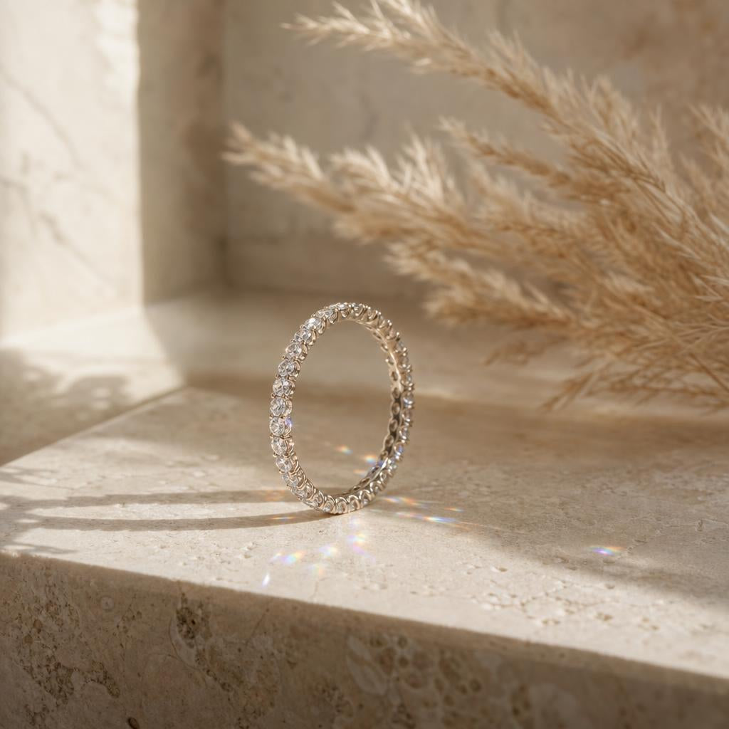 Sparkling moissanite eternity wedding band on a warm cream stone surface