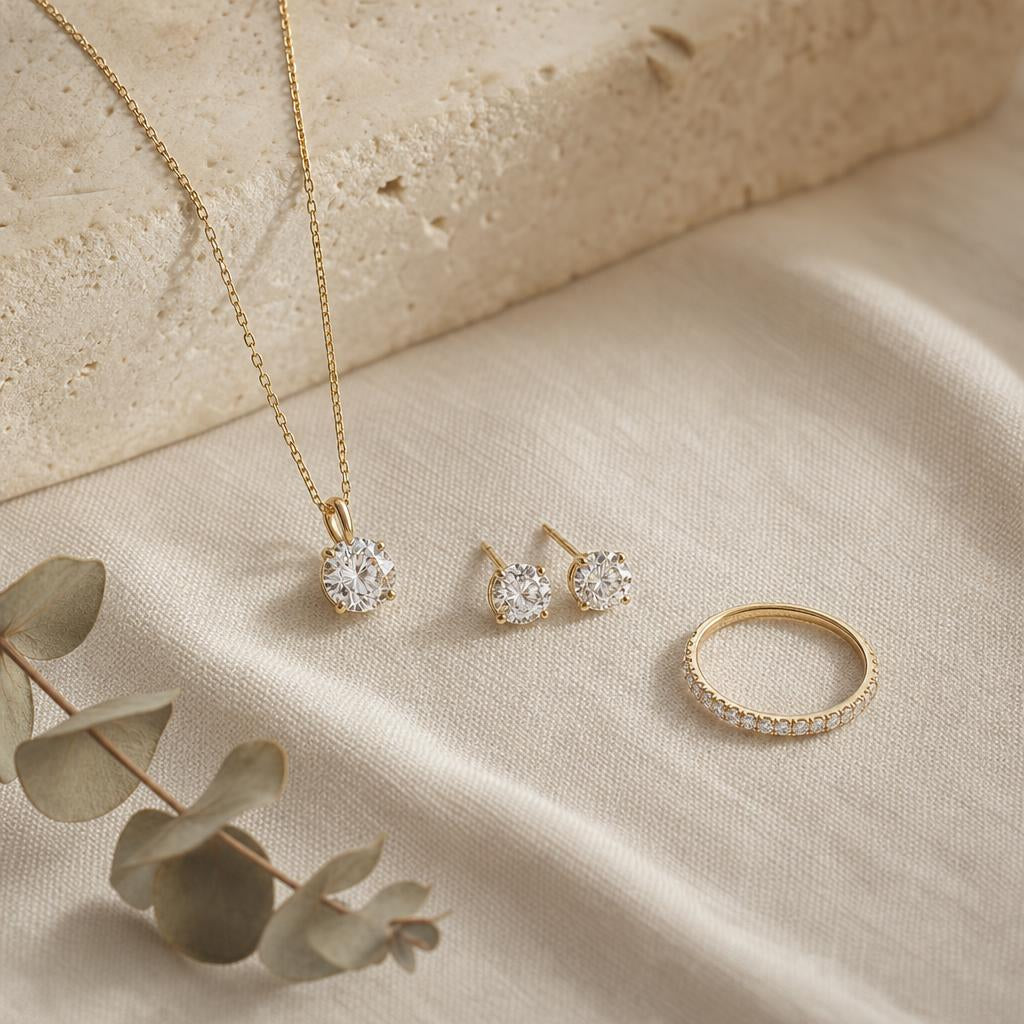 Three graduated sparkling jewelry pieces arranged on warm cream linen