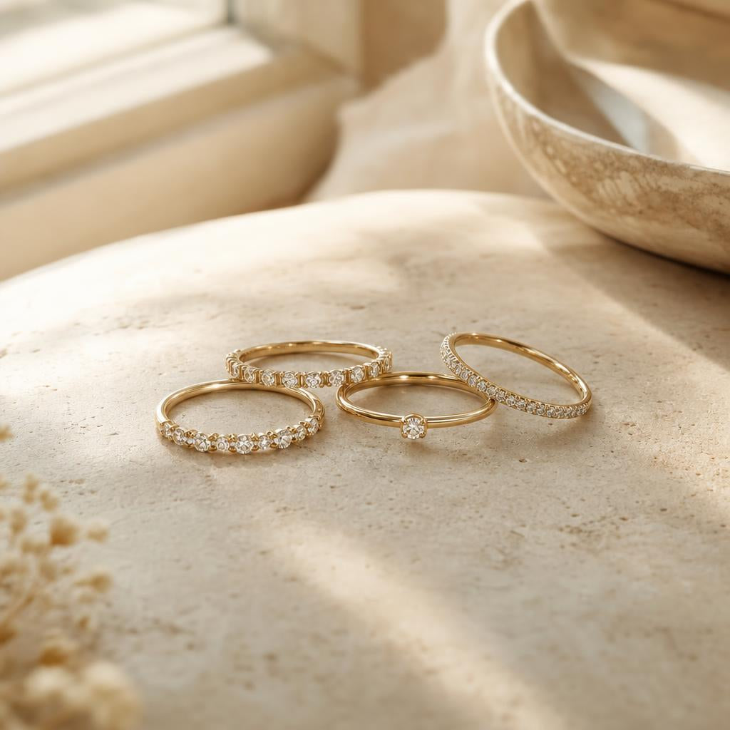 Small cluster of delicate diamond rings arranged on warm cream stone surface
