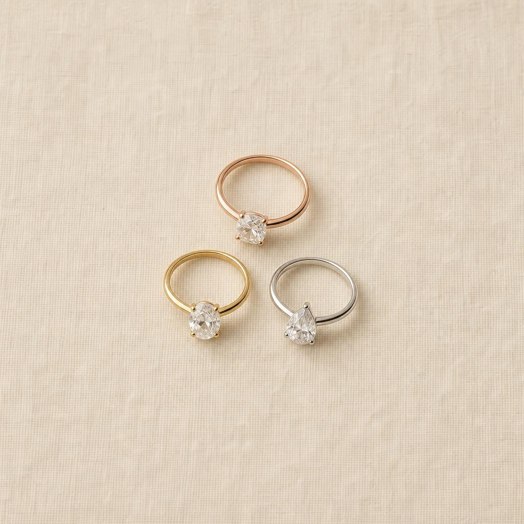 Three rings in rose gold, yellow gold, and white gold arranged on a cream linen surface