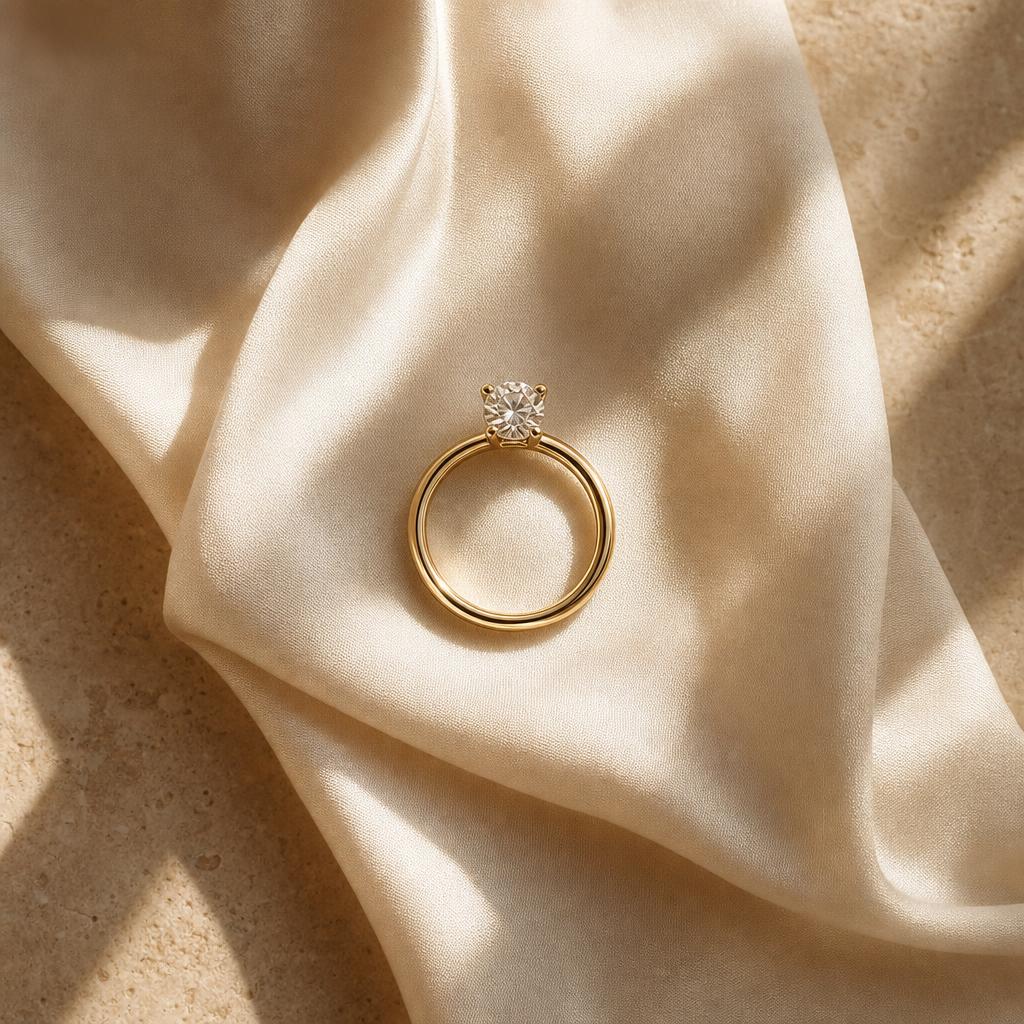 Single solitaire ring resting on warm ivory silk in soft natural light