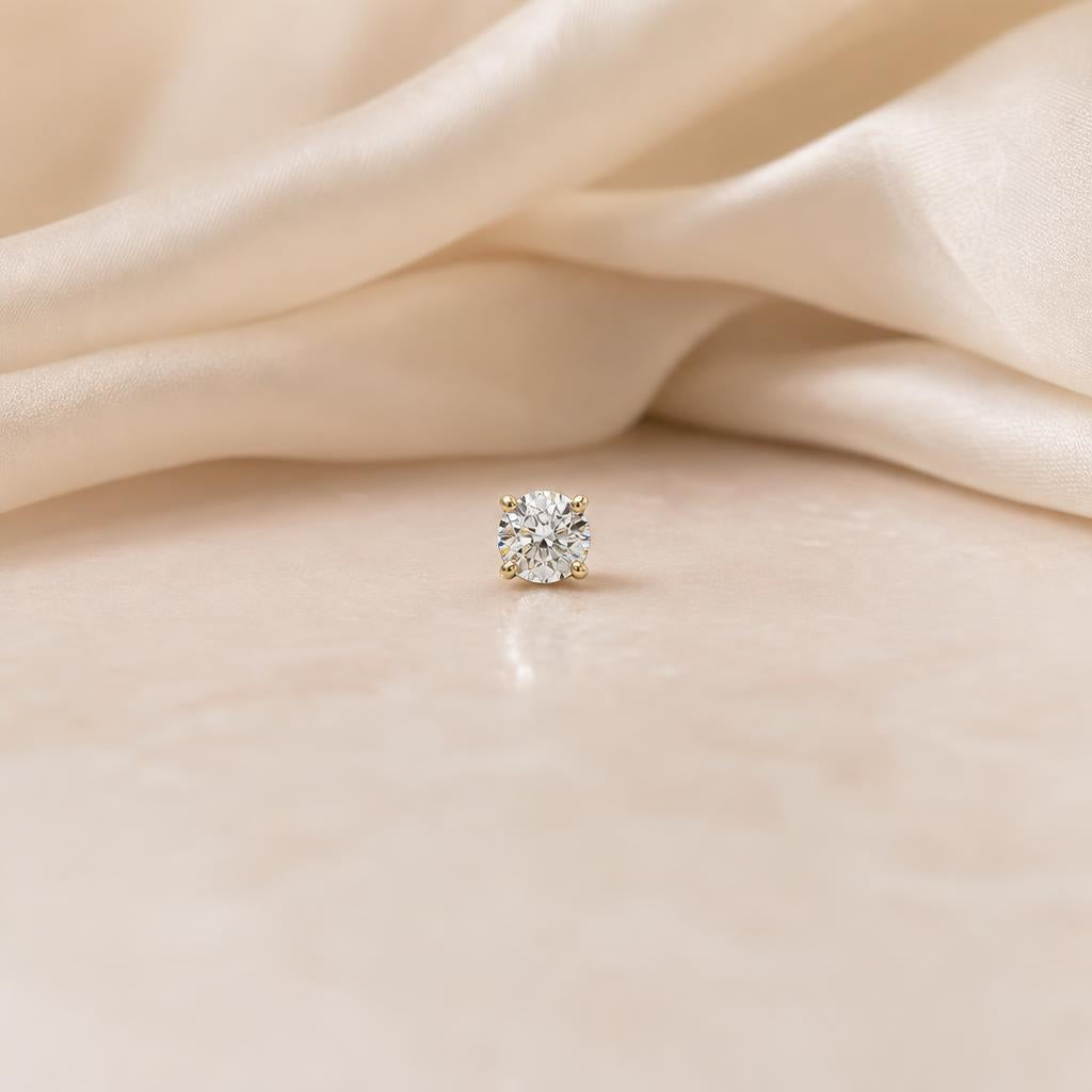 Single sparkling stud earring centered on soft cream silk background