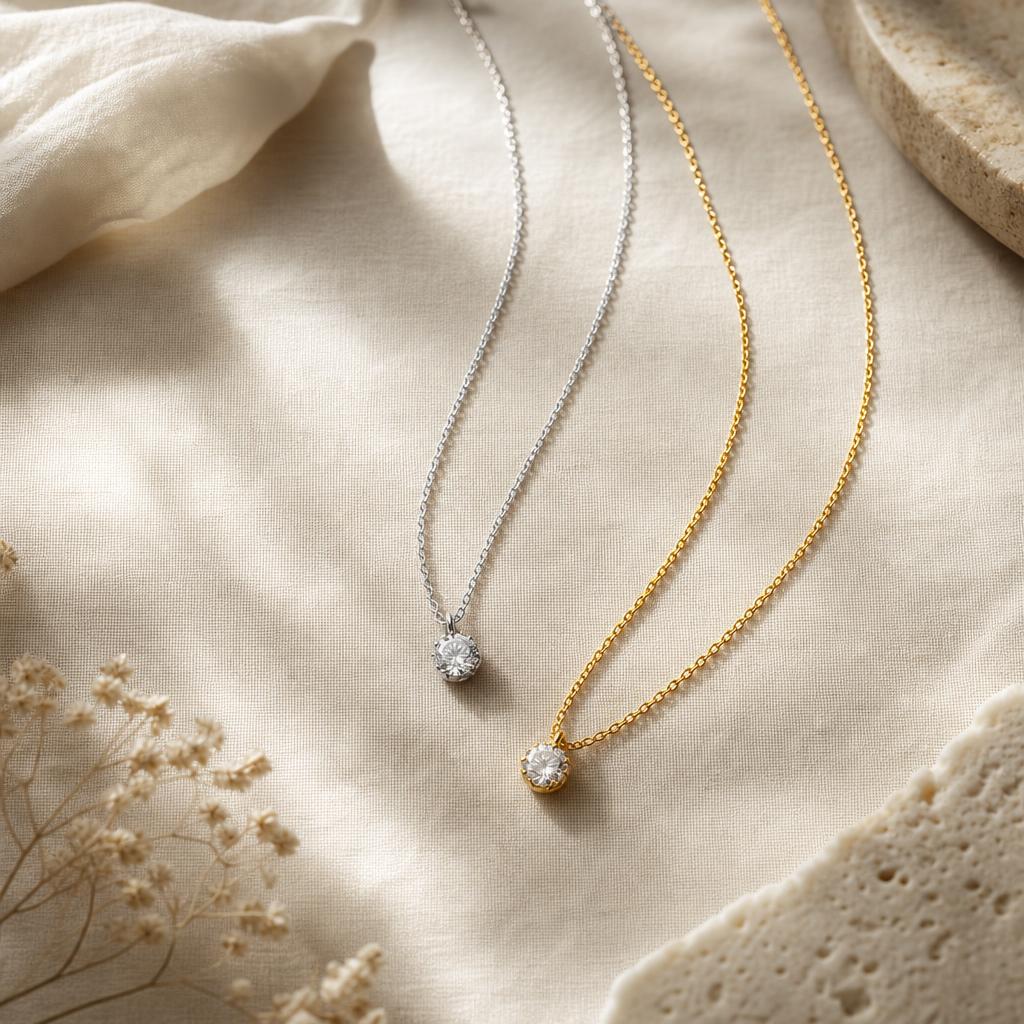 Silver and gold necklace chains with pendants side by side on cream fabric