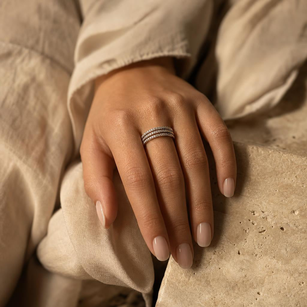 Hand with manicured nails wearing three thin stacked sterling silver rings