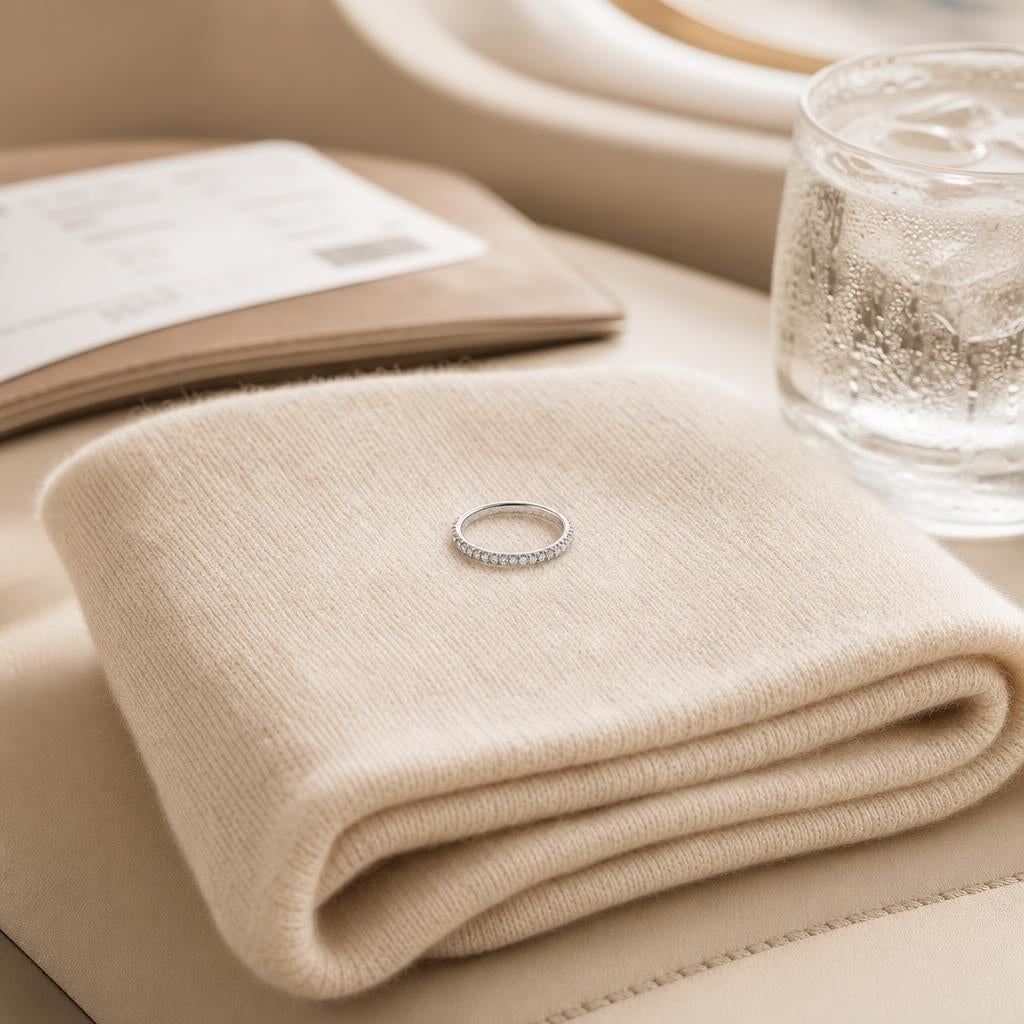 Delicate silver ring resting on cream travel wrap beside water glass