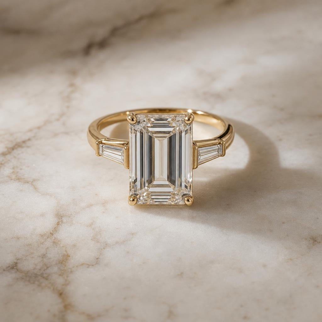 An emerald cut ring resting on marble in soft natural light