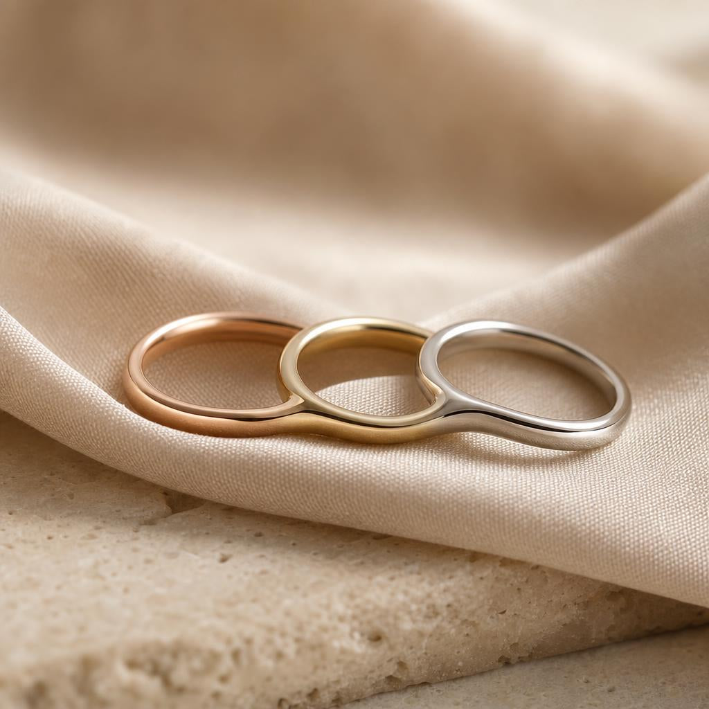Three slender metal stacking rings nestled together on warm cream silk fabric