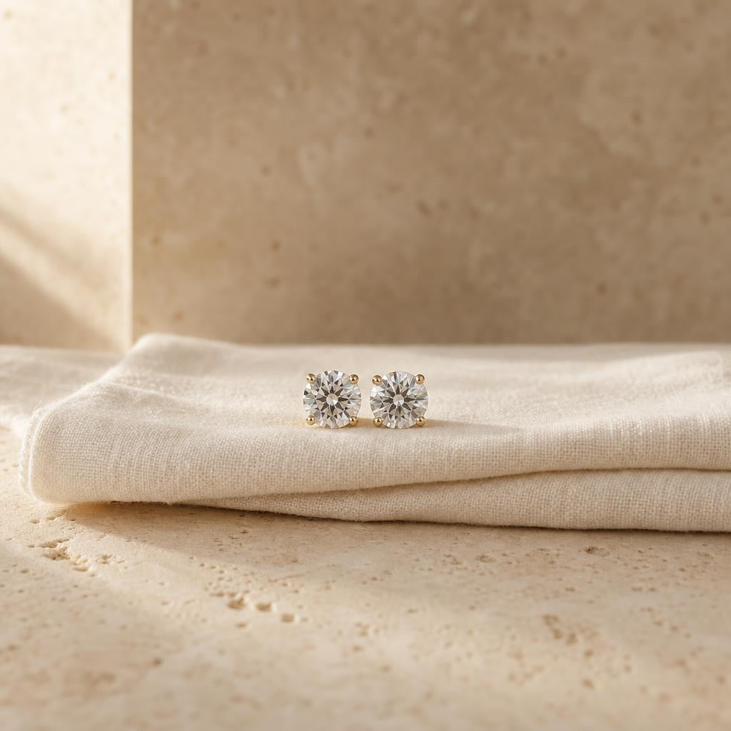 Pair of round stud earrings on cream linen and warm travertine stone