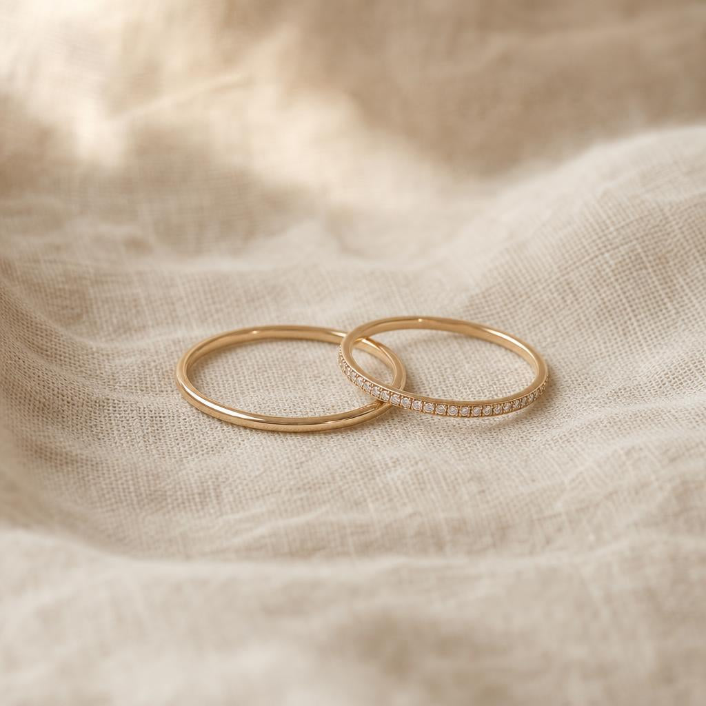 Two thin silver rings, one plain and one pavé, resting on cream linen