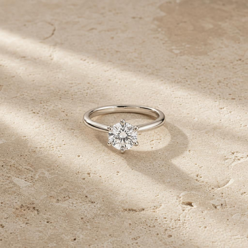 Single solitaire diamond ring centered on warm neutral stone surface