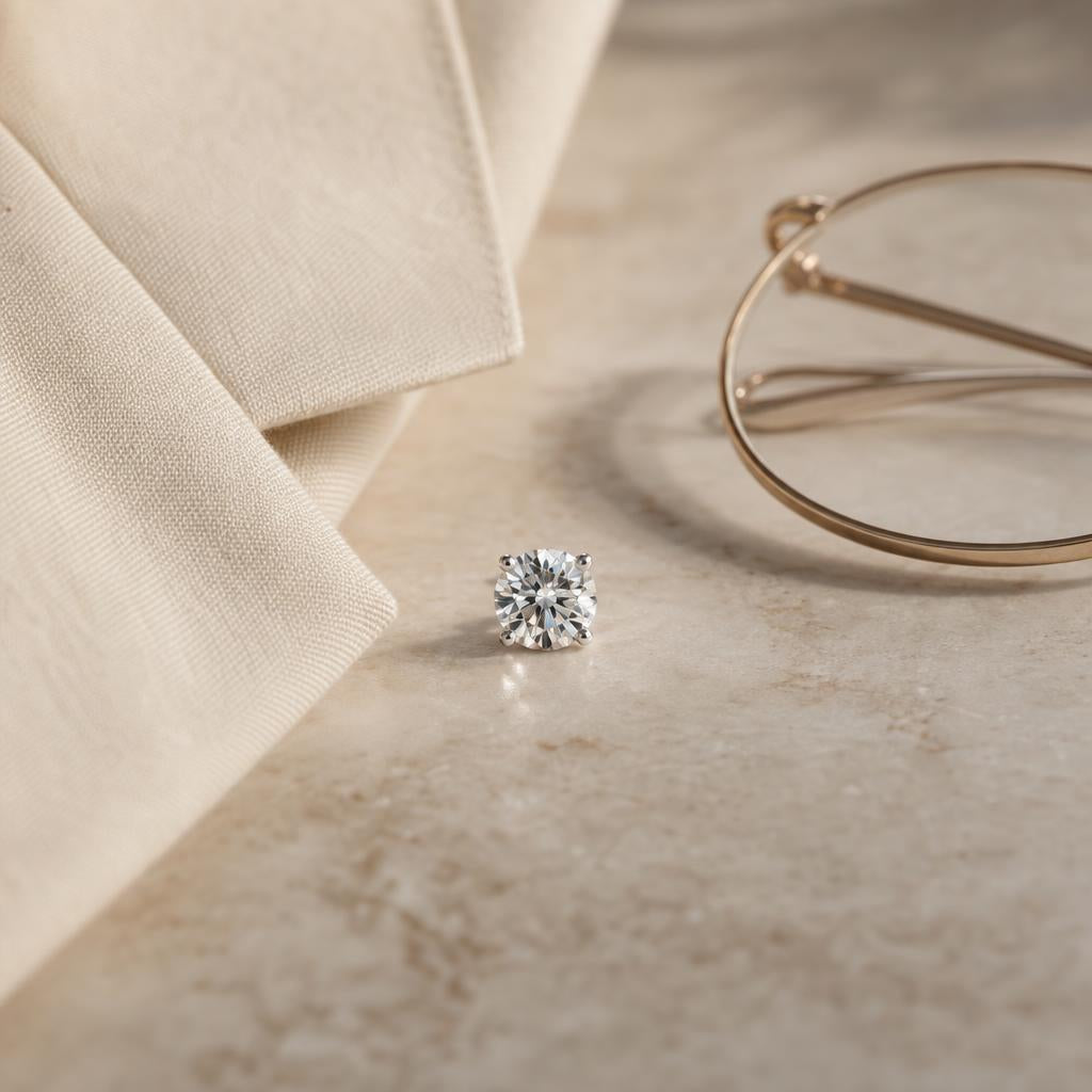 Simulated diamond stud earring beside a folded blazer lapel and glasses